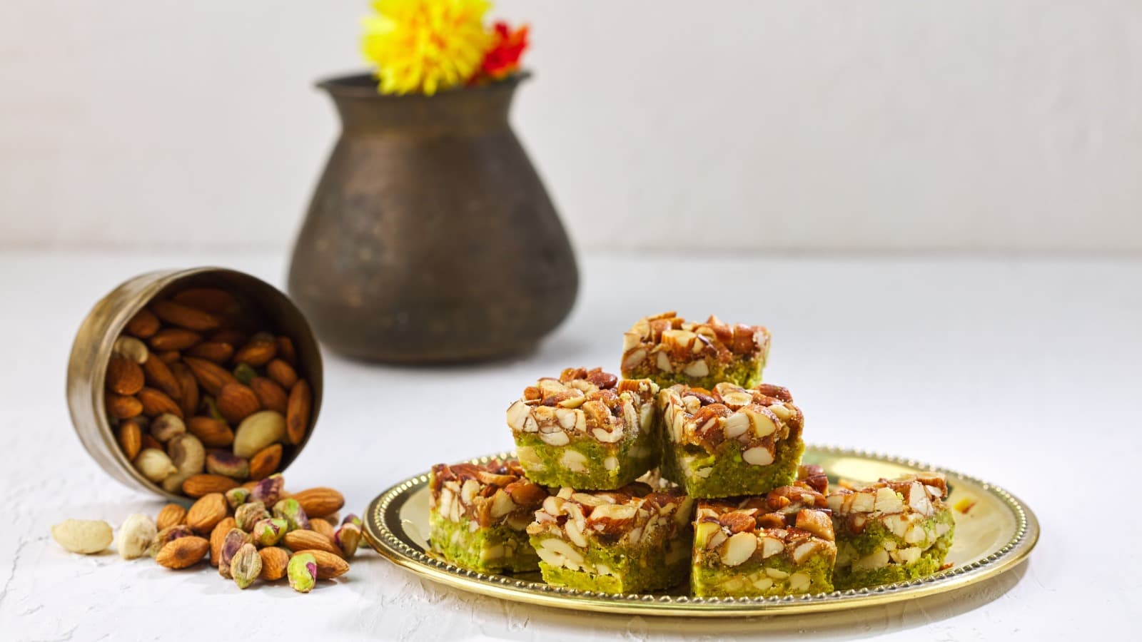 Pista-almond barfi on a gold thali with roasted nuts